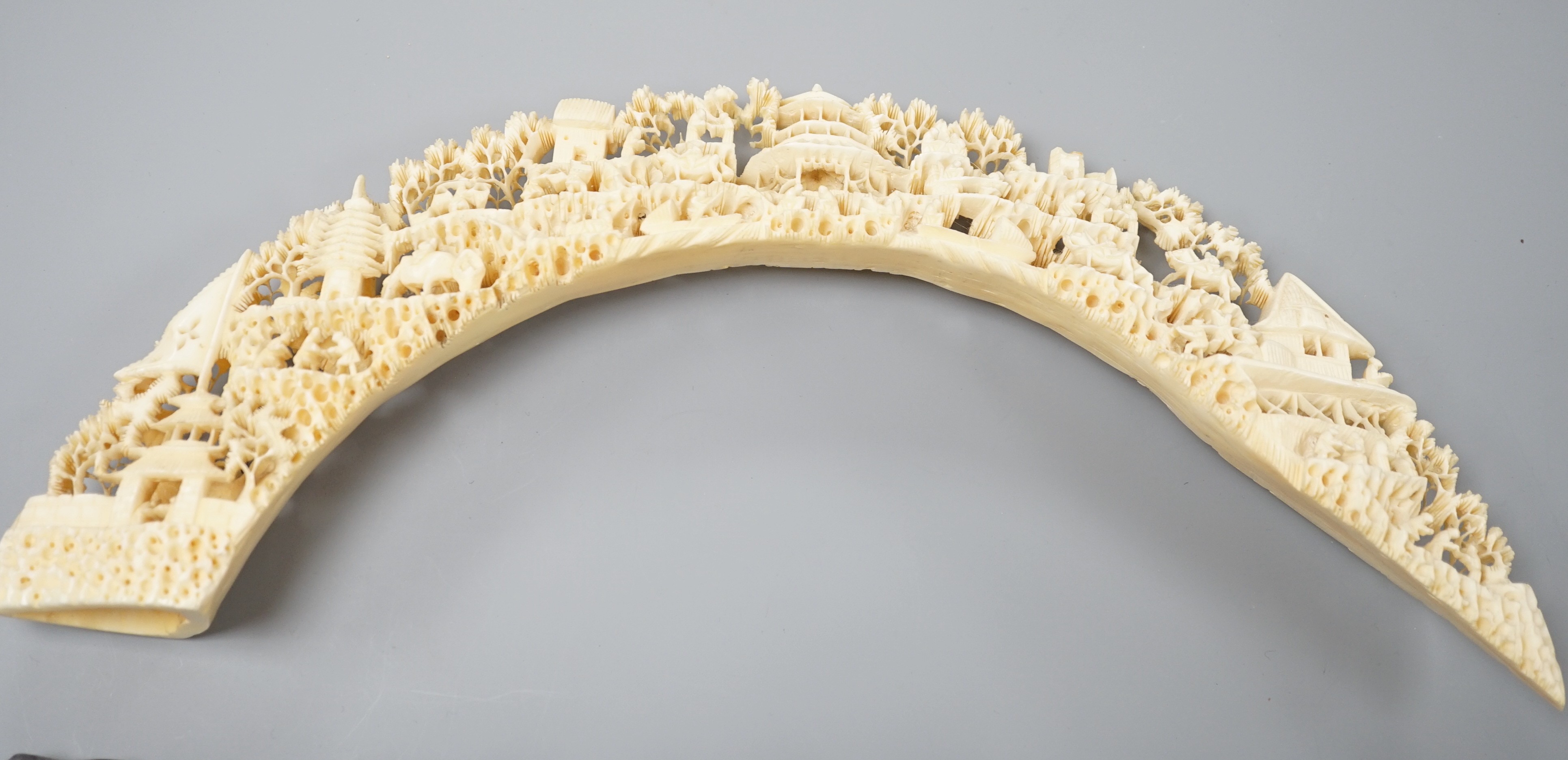 An early 20th century Chinese ivory ‘dragon’ box and cover, and a boar’s tusk carving of figures amid pavilions 40cm